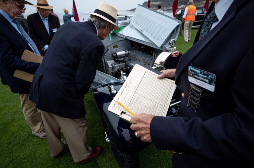 Các thẩm phán kiểm tra một chiếc Bugatti Type 44 Pourtout Cabriolet năm 1928 tại Pebble Beach Concours d'Elegance năm 2021. Trong suốt buổi triển lãm, họ đánh giá xuất xứ, lịch sử và cam kết khôi phục chính xác từng chiếc xe. Vào cuối ngày, những người chiến thắng được công bố trước sự ngưỡng mộ của những người hâm mộ, họ uống rượu Champagne.