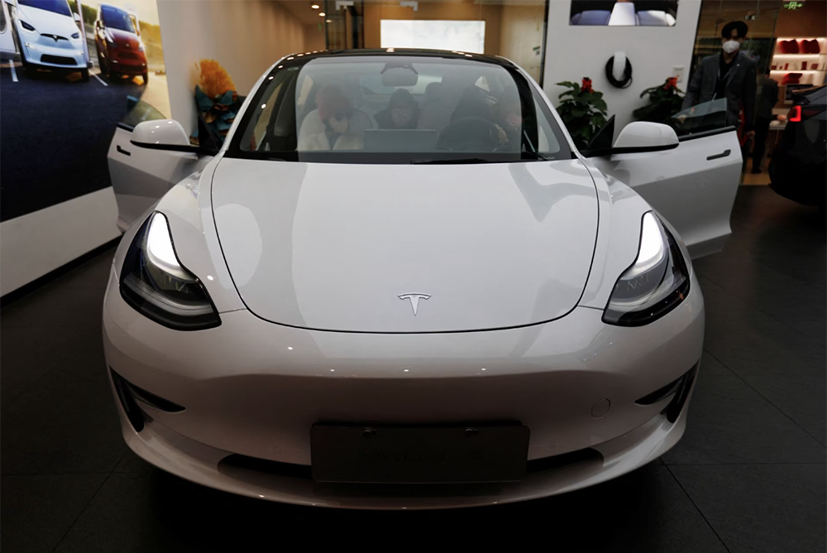 Khách tham quan kiểm tra ô tô Tesla Model 3 bên cạnh Model Y tại showroom.