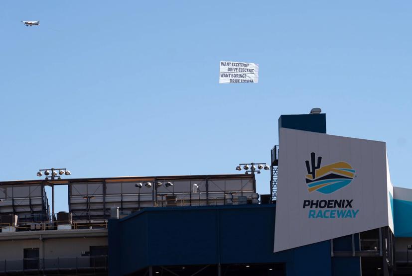 Một chiếc máy bay được tài trợ bởi nhóm Public Citizen đã bay qua Đường đua Phoenix ở Arizona mang theo biểu ngữ đả kích: “Muốn thú vị không? Lái xe điện. Muốn nhàm chán? Lái Toyota”. Ảnh: David Wallace.