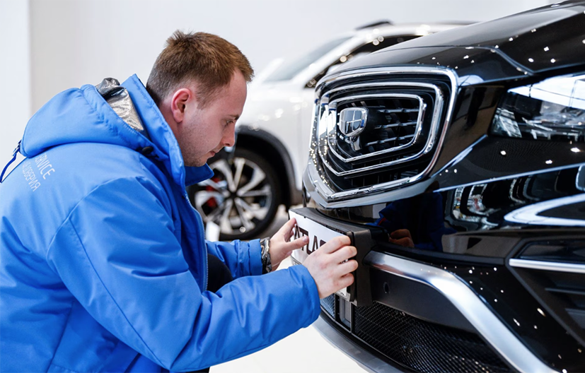 Một nhân viên gắn biển cho một chiếc ô tô do nhà sản xuất ô tô Trung Quốc Geely sản xuất tại một đại lý ở Moscow, Nga, ngày 23 tháng 3 năm 2023. Ảnh: Reuters.