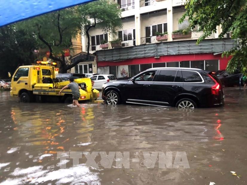 Nhiều ô tô khó khăn lưu thông trên phố Phan Bội Châu hôm nay vì ngập nước. Ảnh: TTXVN